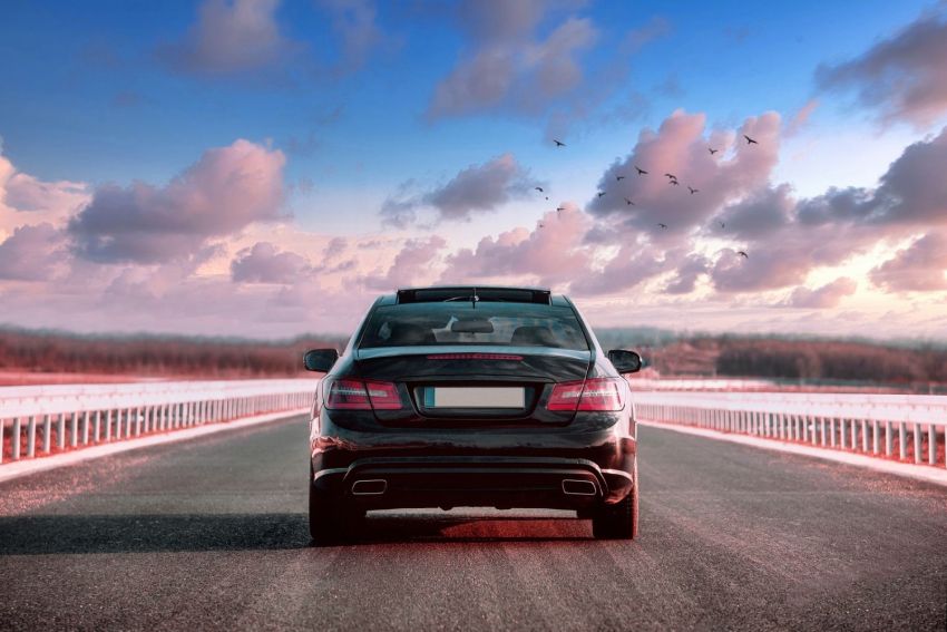 luxurious black car riding in the street with a beautiful sky